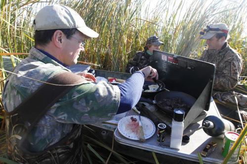 BORIS.MINKEVICH@FREEPRESS.MB.CA  101018 BORIS MINKEVICH / WINNIPEG FREE PRESS Delta President Rob Olson cooks up a duck breakfast right on the canoe in Delta Marsh. In the photo is Jim Fisher and food writer Wendy Burke.