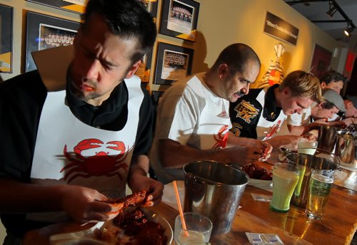Brandon Sun Reigning hot wings eating champion Tyler Crayston (left) dips into hot pepper-laced chicken during the Hot Wings Media Challenge, Tuesday evening at Canad Inns. Crayston, along with Ben Hernandez and Wheat Kings player Brody Melnychuk among others, were raising funds for the local chapter of the Kidney Foundation of Canada.  (Colin Corneau/Brandon Sun)