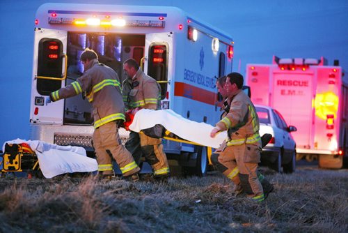 Brandon Sun 16112010 Brandon Fire and Emergency Services members carry the driver of a Jeep to a waiting ambulance after a single vehicle rollover on Veterans Way east of Brandon on Tuesday evening. The driver was taken to hospital with non-life-threatening injuries. (Tim Smith/Brandon Sun)