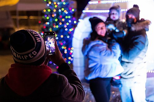Daniel Crump / Winnipeg Free Press. Leo Soriano takes a photo for the Fordyce family with Santa during the 2021 Santa Clause Parade at Shaw Park in Winnipeg. This year the parade remained stationary while families were able to walk up to Santas float to get a selfie with Santa. November 20, 2021.