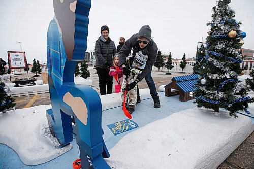 JOHN WOODS / WINNIPEG FREE PRESS
Michael Rathwell helps his son Liam as his cousin, Avery, and grandmother, Susan, look on at the Frozen Fairways attraction in the Polo Park parking lot in Winnipeg on Sunday, November 28, 2021. 

Re: standup