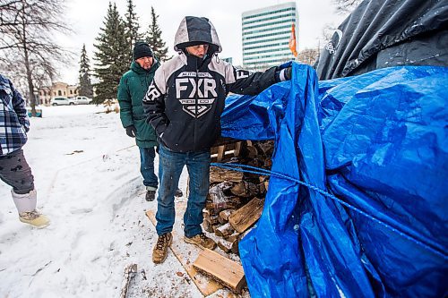 MIKAELA MACKENZIE / WINNIPEG FREE PRESS

John Butler shows the stash of hardwood that they're burning for heat as Willie Nicholas watches at the encampment on the legislative grounds in Winnipeg on Tuesday, Dec. 7, 2021. For Malak story.
Winnipeg Free Press 2021.