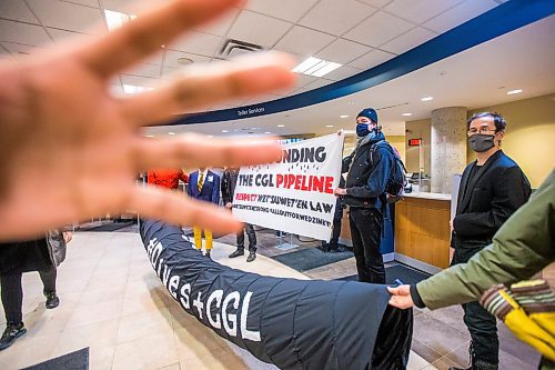 MIKAELA MACKENZIE / WINNIPEG FREE PRESS

A security guard puts their hand in front of the lens during a sit-in organized by Manitoba Energy Justice Coalition in support of the Wet'suwet'en at a downtown RBC bank in Winnipeg on Friday, Dec. 10, 2021. The group is calling for funders of the Coastal Gaslink pipeline to withdraw their support. Standup.
Winnipeg Free Press 2021.