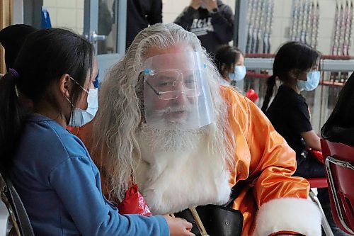 TYLER SEARLE / WINNIPEG FREE PRESS   

Ginew School Grade one student Suraya S., asks Santa to lean in close so she can whisper her Christmas request in his ear. She asked him to bring her dog back to life.
December 13, 2021