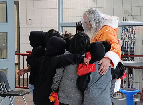 TYLER SEARLE / WINNIPEG FREE PRESS   

Students at Ginew School embrace Santa in a hug Monday afternoon after he stopped by to bring them gifts and Christmas cheer. 
December 13, 2021