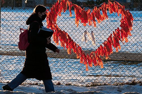 MIKE DEAL / WINNIPEG FREE PRESS
Late afternoon sunlight illuminates orange ribbons on the schoolyard fence at Kelvin High School just as classes are dismissed for the day. The ribbons are a memorial to the unmarked graves at a former residential schools that were discovered this year across the country. 
211214 - Tuesday, December 14, 2021.