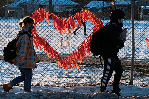 MIKE DEAL / WINNIPEG FREE PRESS
Late afternoon sunlight illuminates orange ribbons on the schoolyard fence at Kelvin High School just as classes are dismissed for the day. The ribbons are a memorial to the unmarked graves at a former residential schools that were discovered this year across the country. 
211214 - Tuesday, December 14, 2021.