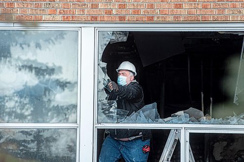 Mike Sudoma / Winnipeg Free Press
A worker pulls glass out of a broken window on the first floor of St James Collegiate Sunday afternoon after a fire broke out Sunday morning. 
December 19, 2021 