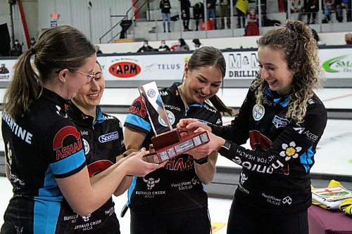 Lead Lauren Lenentine, left, second Emily Zacharias, third Karlee Burgess and skip Mackenzie Zacharias examine the Manitoba Scotties Tournament of Hearts championship trophy after winning their first provincial title on Sunday evening in Carberry. (Lucas Punkari/The Brandon Sun)