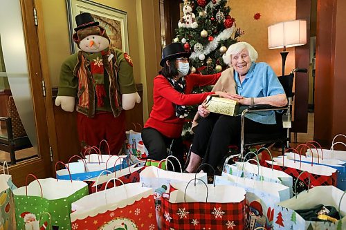 RUTH BONNEVILLE / WINNIPEG FREE PRESS
 
Local -  Convalescent Home Feature

Convalescent Home of Winnipeg resident, Mildred Giesbrecht, 105 years old, enjoys opening her gifts from the home presented to her by staff, Sherry Heppner, development coordinator (red), and Kiran Benipal recreation manager (orange), in front of their Christmas tree in the home's foyer this week.  

One of the gifts given to residents was a shawl which the staff tried on Mildred after it was opened.  

Photos for Christmas feature on how this PCH is adapting to their second pandemic Christmas. Sherry with gifts.

Dec 21st,  2021
