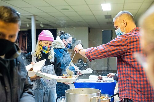 MIKAELA MACKENZIE / WINNIPEG FREE PRESS

Kurt Hollander (right) ladles gravy into a hot Christmas meal that Magnolia Hollander packs up at the Mission Baptist Church in Winnipeg on Saturday, Dec. 25, 2021.  For Malak story.
Winnipeg Free Press 2021.