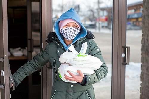 MIKAELA MACKENZIE / WINNIPEG FREE PRESS

Natalie Kirton walk out of the Mission Baptist Church with hot Christmas meals at in Winnipeg on Saturday, Dec. 25, 2021.  For Malak story.
Winnipeg Free Press 2021.