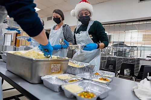 Cristina Robbins and her fellow volunteers prepare free holiday meals for Westman and Area Traditional Christmas Dinner deliveries Saturday at Crocus Plains Regional Secondary School. (Chelsea Kemp/The Brandon Sun)