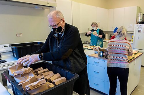 Dean Don Bernhardt packs Christmas lunch bags at St. Matthew's Anglican Cathedral Friday. (Chelsea Kemp/The Brandon Sun)