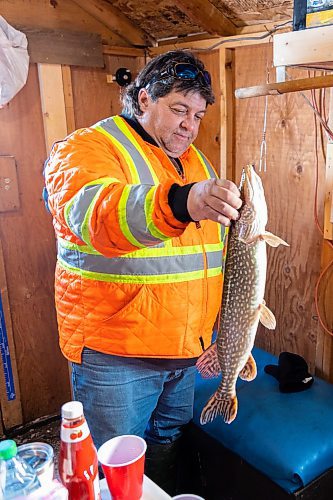 Darcy Robins holds a jack fish in his family ice fishing shack at Lake Wahtopanah on Tuesday, Dec. 28. (Chelsea Kemp/The Brandon Sun)