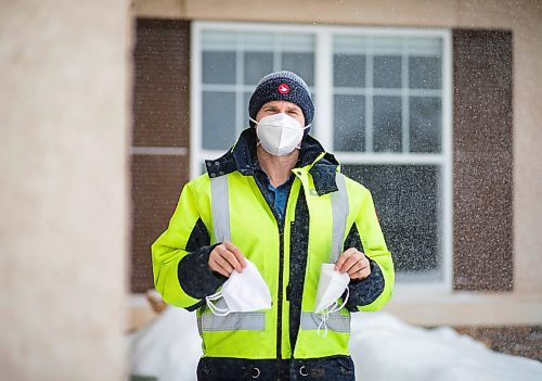 JESSICA LEE / WINNIPEG FREE PRESS

Letter-carrier Corey Gallagher poses for a photo at his home on January 18, 2022. He was sent home earlier in the day from his work at Canada Post because his boss said he couldn&#x2019;t wear a medical grade N95 to work. The supervisors and superintendent insisted he wear the provided cloth mask he is holding in his left hand. He holds the N95 he was initially wearing to work in his other hand. 

Reporter: Dylan






