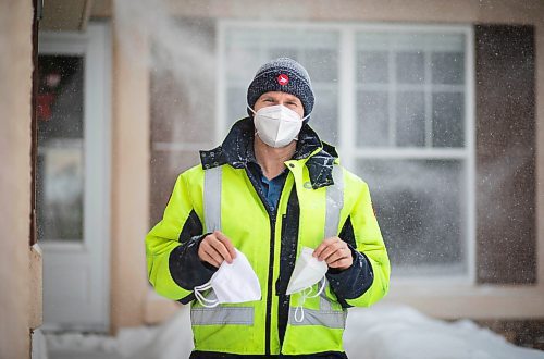 JESSICA LEE / WINNIPEG FREE PRESS

Letter-carrier Corey Gallagher poses for a photo at his home on January 18, 2022. He was sent home earlier in the day from his work at Canada Post because his boss said he couldn&#x2019;t wear a medical grade N95 to work. The supervisors and superintendent insisted he wear the provided cloth mask he is holding in his left hand. He holds the N95 he was initially wearing to work in his other hand. 

Reporter: Dylan






