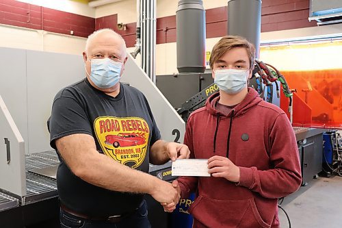 Road Rebels president Dave Burba hands a cheque worth $250 to Connor Guymer at Crocus Plains Regional Secondary School on Friday afternoon. A total of seven Crocus automotive students received a similar grant from the Road Rebels and Brandon and Area Car Enthusiasts on Friday for their classroom performance over the past two years. (Kyle Darbyson/The Brandon Sun) 