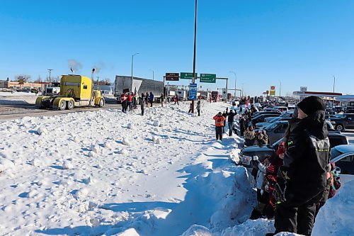 Bystanders watch a convoy of trucks pass through Brandon along the Trans Canada Highway on Tuesday morning. The convoy is bound for Ottawa as part of a protest against federal pandemic restrictions and vaccine mandates. (Kyle Darbyson/The Brandon Sun)