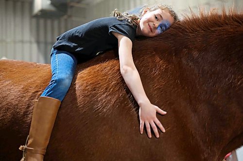 Then seven-year-old Riya Belcher of Brandon cuddles with Vinnie, a Clydesdale owned by Heather and Chris Arthur of Gentrice Farms, during the Royal Manitoba Winter Fair in 2019. (FILE/The Brandon Sun)