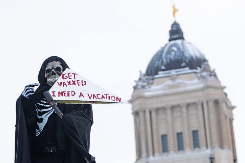 Daniel Crump / Winnipeg Free Press. A  counter protestor dressed as the grim reaper stands at the he trucker convoy protest at the Manitoba legislature Saturday in Winnipeg. February 5, 2022.