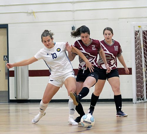 Brandon University Bobcats Kylie Van De Woestyne tackles Assiniboine Community College Cougars Calista Green as Megan Beswitherick looks on during their Manitoba Colleges Athletic Conference women's futsal game at ACC on Sunday. (Thomas Friesen/The Brandon Sun)