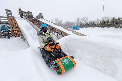 Daniel Crump / Winnipeg Free Press. JC Bottomley (adult) and Liam take a ride on the toboggan slide on pening day of Festival du Voyageur in Winnipeg. The Festival returns for the first time since prior to the pandemic. February 19, 2022.