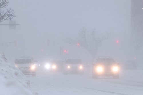 Daniel Crump / Winnipeg Free Press. Cars move along Portage Ave. Saturday afternoon as a blizzard reduces visibility significantly. February 19, 2022.