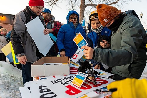 Community members collect signs for the Stand with Ukraine Rally in front of Dauphin City Hall Wednesday.(Chelsea Kemp/The Brandon Sun)