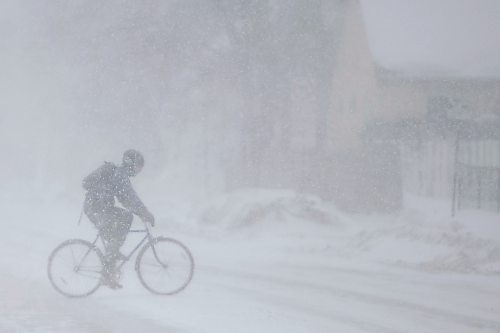Daniel Crump / Winnipeg Free Press. A cyclist crosses Arlington street as heavy and blowing snow make for treacherous road conditions Saturday afternoon. March 12, 2022.