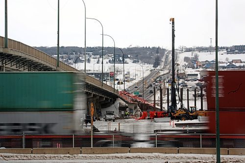 The space between two moving Canadian Pacific Railway cars allows a view of the pile driver and work crew starting construction of the new Daly Overpass along 18th Street on Monday afternoon. (Matt Goerzen/The Brandon Sun)