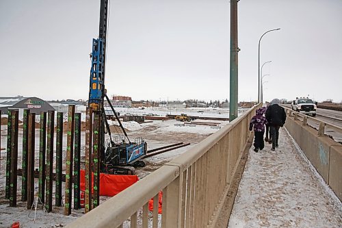 A trio of pedestrians crossing the Daly Overpass walkway watch a pile driver and work crew in action on Monday afternoon. Construction of the new Daly Overpass bridge began earlier this year.  (Matt Goerzen/The Brandon Sun)