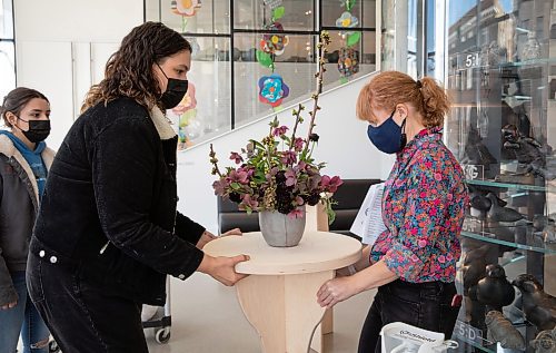 JESSICA LEE / WINNIPEG FREE PRESS

Nicole Tomala (left) and Colleen Leduc move a table with flowers on it at Winnipeg Art Gallery on March 31, 2022, in preparation for the Art in Bloom event which takes place Saturday.