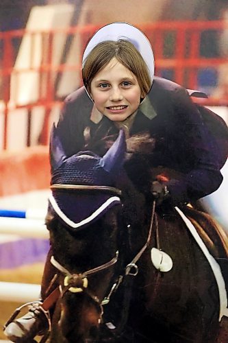 31032022
Rylee Dyck peers through a horse jumping cut-out during the Royal Manitoba Winter Fair on Thursday. 
(Tim Smith/The Brandon Sun)