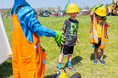 Lucas Black, 5, left and Enzo Lisa, 4, try on construction gear during Touch-a-Truck at the Keystone Centre grounds Saturday. (Chelsea Kemp/The Brandon Sun)