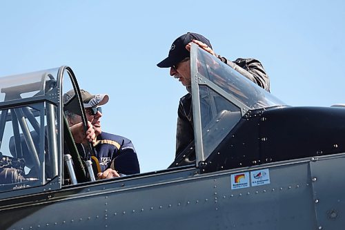 Commonwealth Air Training Plan Museum volunteer Mike Toews shows a curious tourist the cockpit of a 1952 North American Harvard aircraft on Sunday morning in Brandon. While this plane does not belong to the museum, Sunday's Canadian Armed Forces Day celebration featured a number of privately-owned aircrafts as well. (Kyle Darbyson/The Brandon Sun)