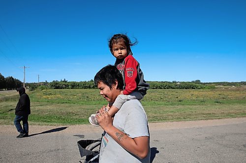 09092022
Steven Wasicuna carries his step-child Tesalyn Taylor on his shoulders while walking with Nellie Branth during the Suicide Awareness Walk at Sioux Valley Dakota Nation on Friday. The goal of the walk was to raise suicide prevention awareness, to bring attention to supports for those struggling and to support families who have been affected by losing loved ones. Speakers addressed participants before and after the walk.  (Tim Smith/The Brandon Sun)
