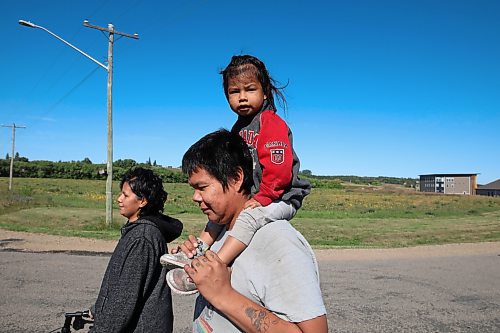 09092022
Steven Wasicuna carries his step-child Tesalyn Taylor on his shoulders while walking with Nellie Branth during the Suicide Awareness Walk at Sioux Valley Dakota Nation on Friday. The goal of the walk was to raise suicide prevention awareness, to bring attention to supports for those struggling and to support families who have been affected by losing loved ones. Speakers addressed participants before and after the walk.  (Tim Smith/The Brandon Sun)
