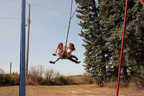 12092022
Makenzie Cousley and Skyler Smith swing at Edrans Christian School in the small community of Edrans, north of Sidney, Manitoba, during lunch recess on a hot Monday. The private school currently has eight students between grades K-9 enrolled.  (Tim Smith/The Brandon Sun)
