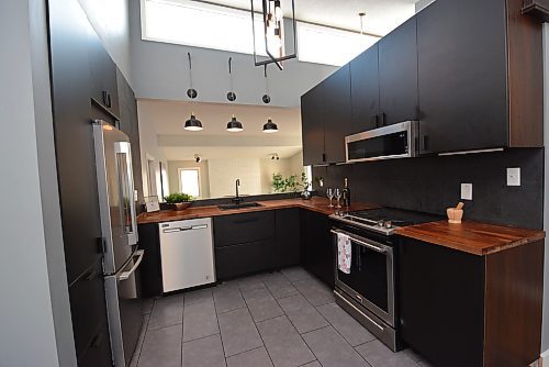 Todd Lewys / Winnipeg Free Press
Set beneath a vaulted ceiling with a bank of windows up high, the remodelled kitchen comes with a grey tile floor, butcher block countertops, a wealth of black cabinets and stainless appliances.