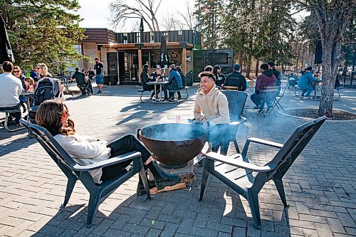 Daniel Crump / Winnipeg Free Press. Luciana Lazo and Carl Alfaro enjoy a warm spring afternoon beside a fire pit at Cargo Bar at Assiniboine Park. April 24, 2021.