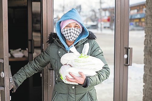 MIKAELA MACKENZIE / WINNIPEG FREE PRESS

Natalie Kirton walk out of the Mission Baptist Church with hot Christmas meals at in Winnipeg on Saturday, Dec. 25, 2021.  For Malak story.
Winnipeg Free Press 2021.