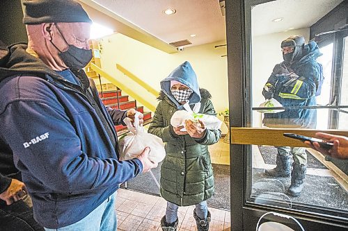 MIKAELA MACKENZIE / WINNIPEG FREE PRESS

Volunteer John Sawatzky (left) hands Natalie Kirton two hot Christmas meals at the Mission Baptist Church in Winnipeg on Saturday, Dec. 25, 2021.  For Malak story.
Winnipeg Free Press 2021.