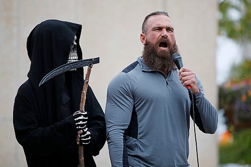 JOHN WOODS / WINNIPEG FREE PRESS
A person dressed as the Grim Reaper looks on as organizer Shaun Zimmer speaks to about 150 anti-maskers/vaxxers gathered at the MB Legislature and walked to the City Hall in protest against COVID-19 vaccinations and masks in Winnipeg Monday, September 13, 2021. 

Reporter: Silva