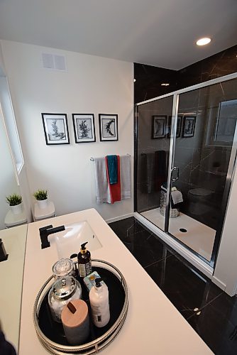 Todd Lewys / Winnipeg Free Press
Black marble on the floor and in the shower contrasts beautifully with an off-white quartz countertop on the flat panel oak vanity to offer the stunning ensuite some contemporary contrast.