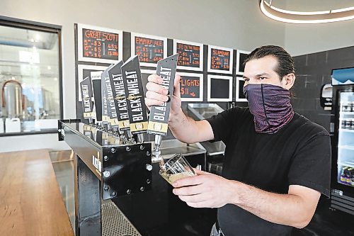 Rob Zichrul, head bartender for Black Wheat Brewing, pours a pint during the opening day of the taproom in 2021.  (File/The Brandon Sun)