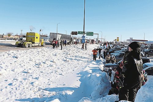 Bystanders watch a convoy of trucks pass through Brandon along the Trans Canada Highway on Tuesday morning. The convoy is bound for Ottawa as part of a protest against federal pandemic restrictions and vaccine mandates. (Kyle Darbyson/The Brandon Sun)