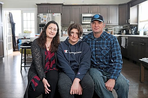 Rainey Delaurier, 13, sits with his parents Cher Andruski and Tom Delaurier, at their home in Brandon on Friday. Delaurier lives with Ollier disease, a rare bone disease, and will be travelling to Montreal this week for surgery.  (Tim Smith/The Brandon Sun)