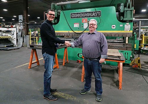 Sean Lepper, vice-president of Behlen Industries (left), congratulates Vince Goldstone on reaching 50 years of work at the company ahead of Goldstone's retirement on Monday. (Joseph Bernacki/The Brandon Sun)