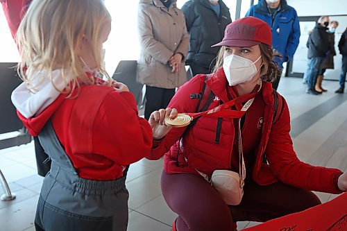 Kristen Campbell shows her gold medal to her cousin's daughter Charleigh Hargreaves, 5, after arriving at the Brandon Municipal Airport on Tuesday. 
(Tim Smith/The Brandon Sun)